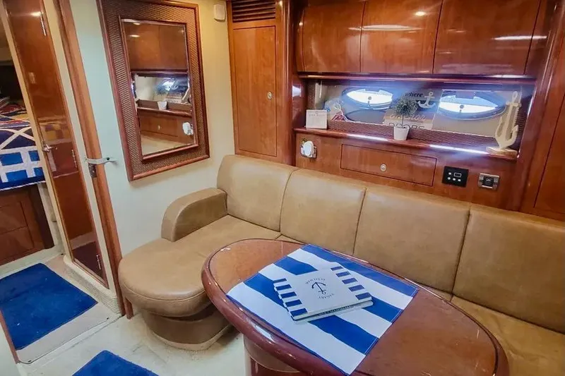 Slide: The Image of 2005 Sea Ray 390 Sundancer interior with beige seating, wooden cabinetry, and nautical decor. - 10