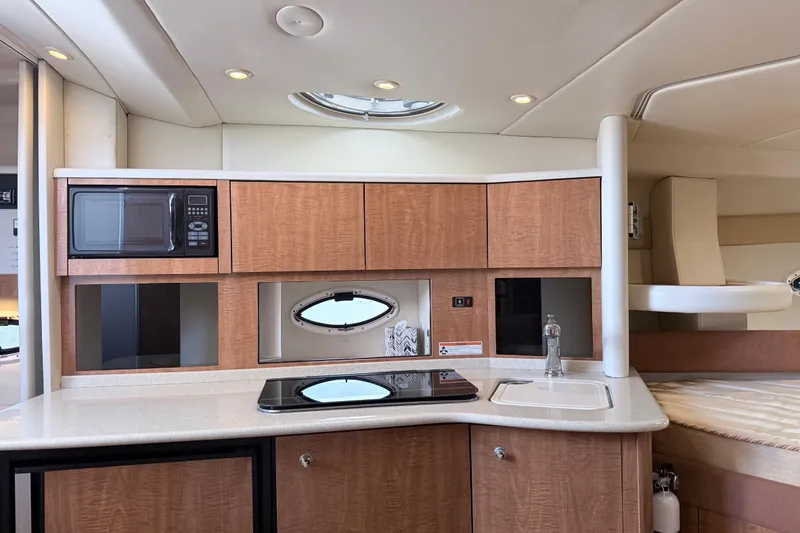 Slide: The Image of 2002 Maxum 3100 SE yacht interior with kitchenette, featuring microwave, stove, and sink. - 12