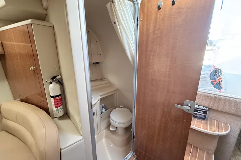 Slide: The Image of 2002 Maxum 3100 SE boat interior with bathroom, wooden cabinetry, and fire extinguisher. - 18