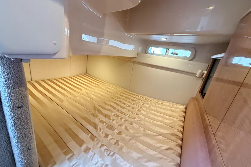 Slide: The Image of 2002 Maxum 3100 SE cabin interior with striped bedding and porthole windows. - 19