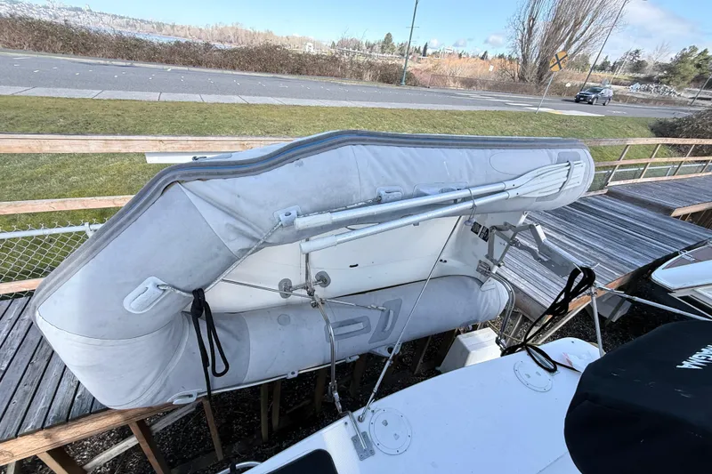 Slide: The Image of 2002 Maxum 3100 SE boat with inflatable dinghy on deck, near waterfront road. - 2