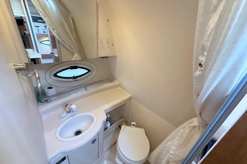 Slide: The Image of 2002 Maxum 3100 SE boat bathroom with sink, toilet, and porthole window. - 20