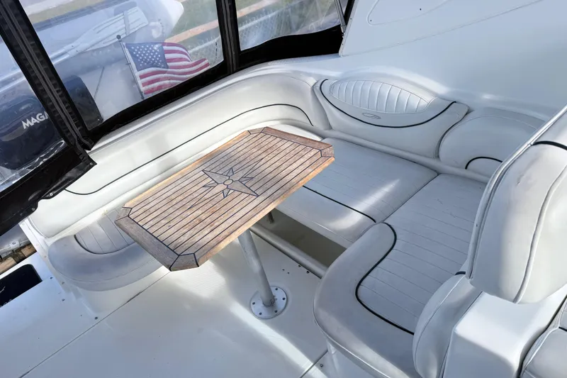 Slide: The Image of 2002 Maxum 3100 SE boat interior with cushioned seating and wooden table. - 8