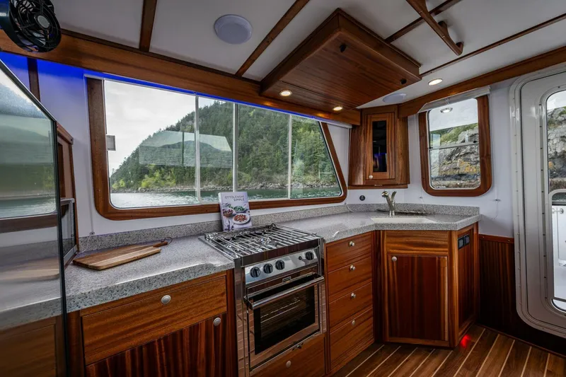 Slide: The Image of 2024 Nordic Tug 40 kitchen with wood cabinetry, modern appliances, and scenic window views. - 6