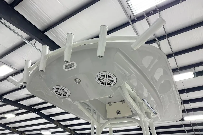 Slide: The Image of 2026 Pathfinder 2200 TRS boat's T-top with rod holders and speakers in a warehouse. - 8