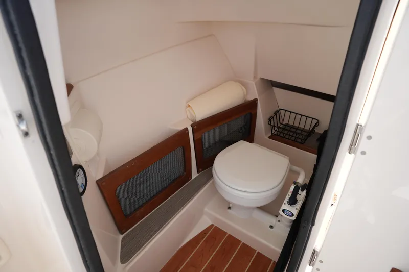 Slide: The Image of 2021 Grady-White Freedom 235 boat interior with compact marine toilet and storage. - 30