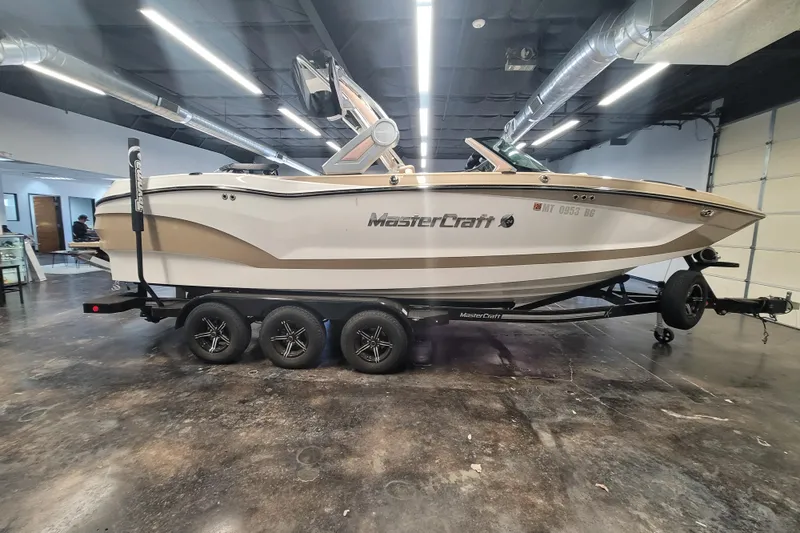 The Image of 2022 MasterCraft X24 boat on trailer in indoor showroom setting. - 1