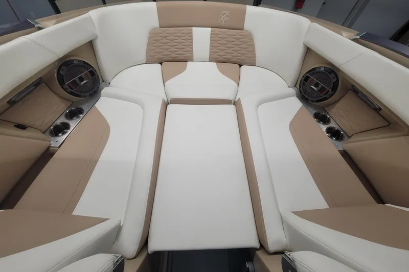 Slide: The Image of 2022 MasterCraft X24 boat interior with beige and white seating, cup holders, and speakers. - 13