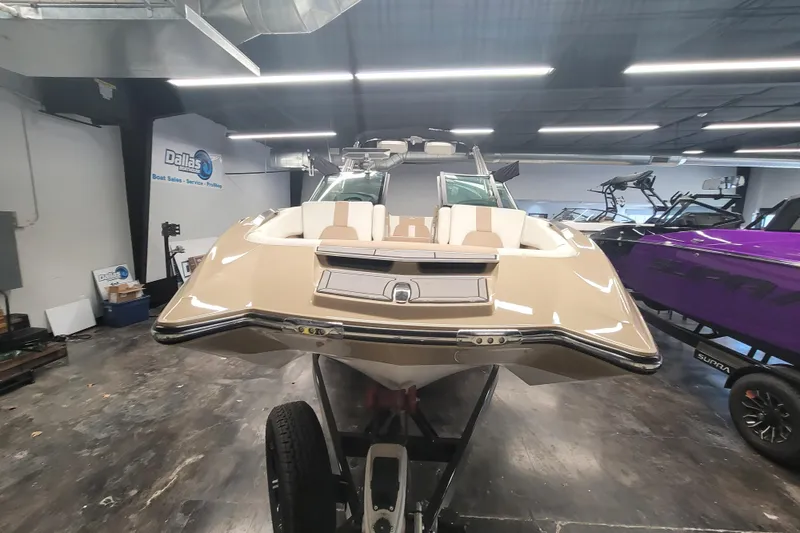 Slide: The Image of 2022 MasterCraft X24 boat in showroom, front view, beige color, indoor lighting. - 4