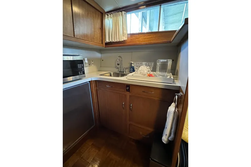 Slide: The Image of 1968 Chris-Craft 35 Commander kitchen with wooden cabinets, sink, and microwave. - 13