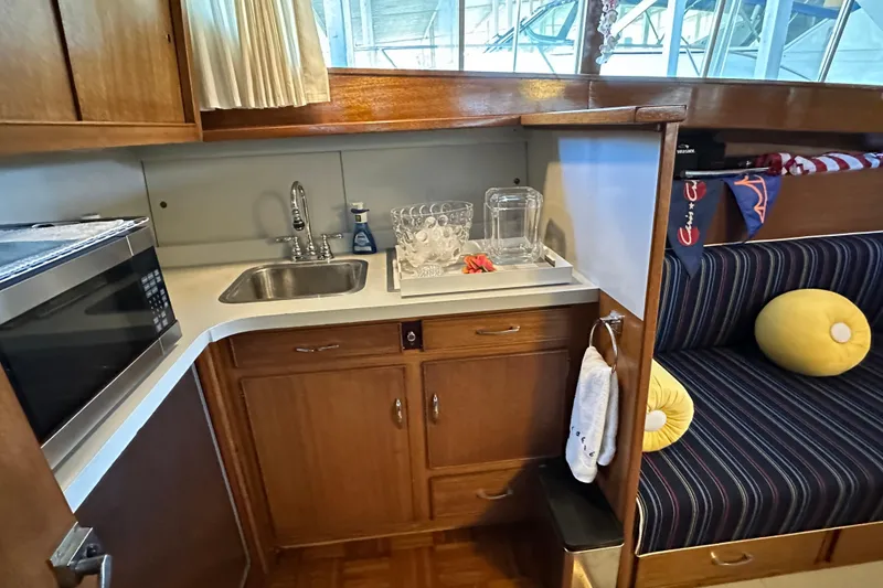 Slide: The Image of 1968 Chris-Craft 35 Commander interior with kitchenette, sink, and striped seating area. - 3