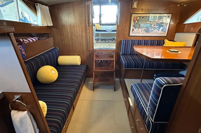 Slide: The Image of 1968 Chris-Craft 35 Commander interior with striped seating, wooden table, and nautical decor. - 6