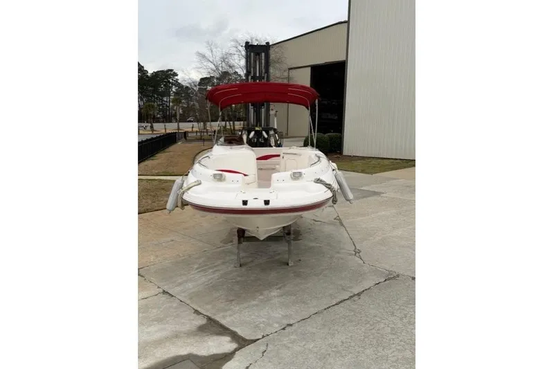 Slide: The Image of 2000 Chaparral 232 Sunesta boat with red canopy, parked outside a building. - 3