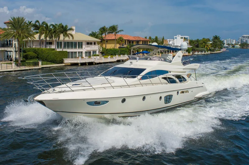 Slide: The Image of 2009 Azimut 62E luxury yacht cruising near waterfront homes. - 2