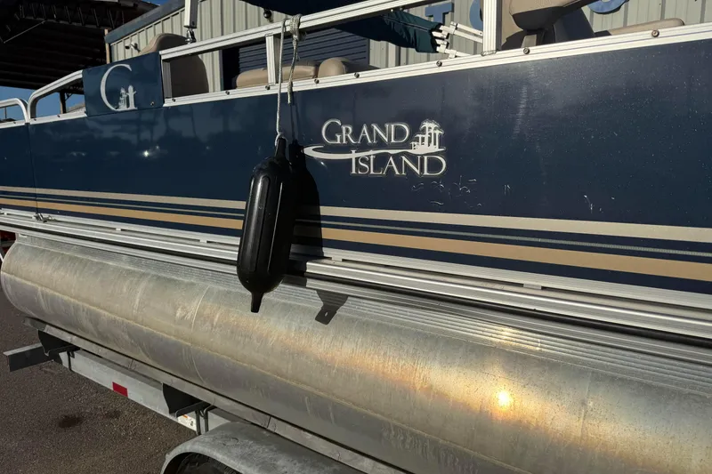 Slide: The Image of 2021 Avalon 2480 GF pontoon boat with "Grand Island" branding, docked on a trailer. - 17
