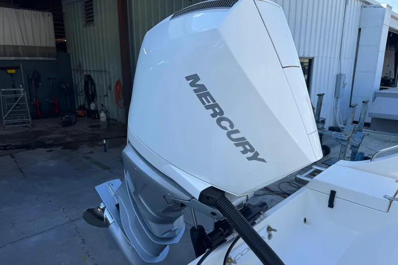 Slide: The Image of 2024 Cobia 237 Center Console with Mercury outboard engine in a boatyard setting. - 11