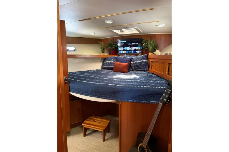 Slide: The Image of Cozy bedroom in 1993 Riviera 47 Open Flybridge yacht with blue bedding and wooden accents. - 16