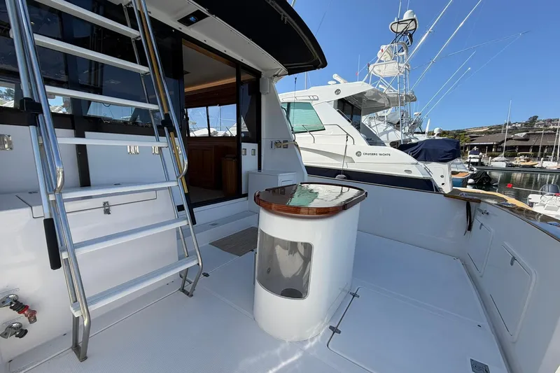 Slide: The Image of 1993 Riviera 47 Open Flybridge yacht docked in a marina, showcasing spacious deck and elegant design. - 26