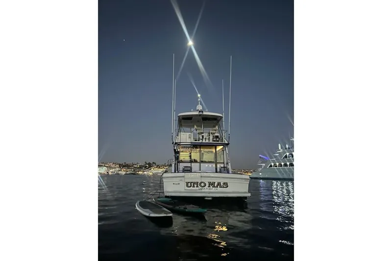 Slide: The Image of 1993 Riviera 47 Open Flybridge yacht illuminated at night on calm water. - 8