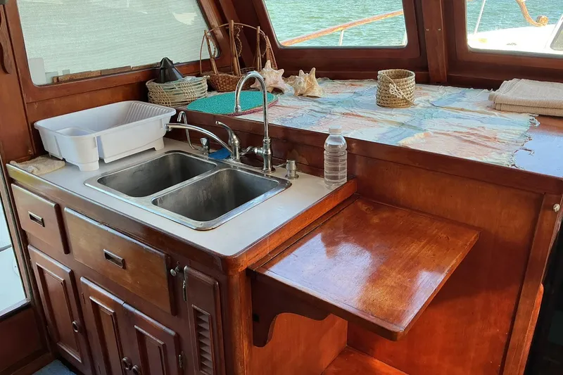 Slide: The Image of 1977 Universal Marine Europa boat kitchen with wooden cabinetry and dual sink. - 17