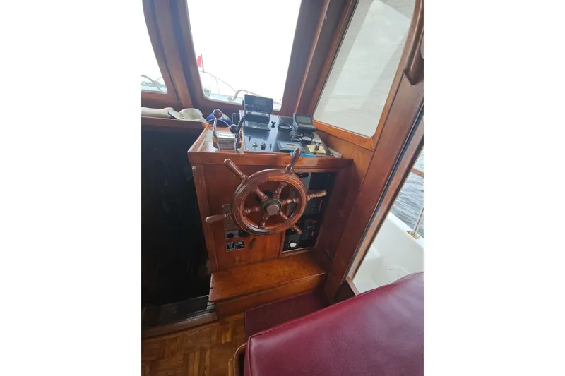 Slide: The Image of 1977 Universal Marine Europa boat helm with wooden steering wheel and navigation controls. - 26