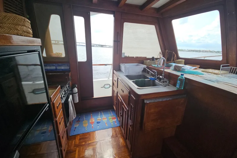 Slide: The Image of 1977 Universal Marine Europa boat kitchen with wooden cabinets, sink, and ocean view. - 28