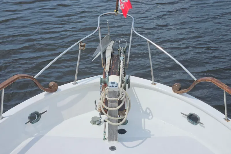 Slide: The Image of Bow of a 1977 Universal Marine Europa boat with anchor and railing on water. - 32