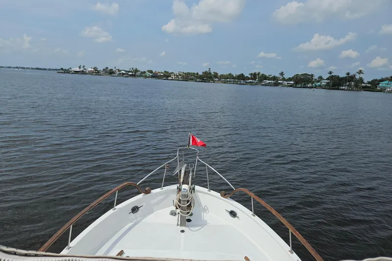 Slide: The Image of Bow of 1977 Universal Marine Europa yacht on calm waters under a partly cloudy sky. - 33