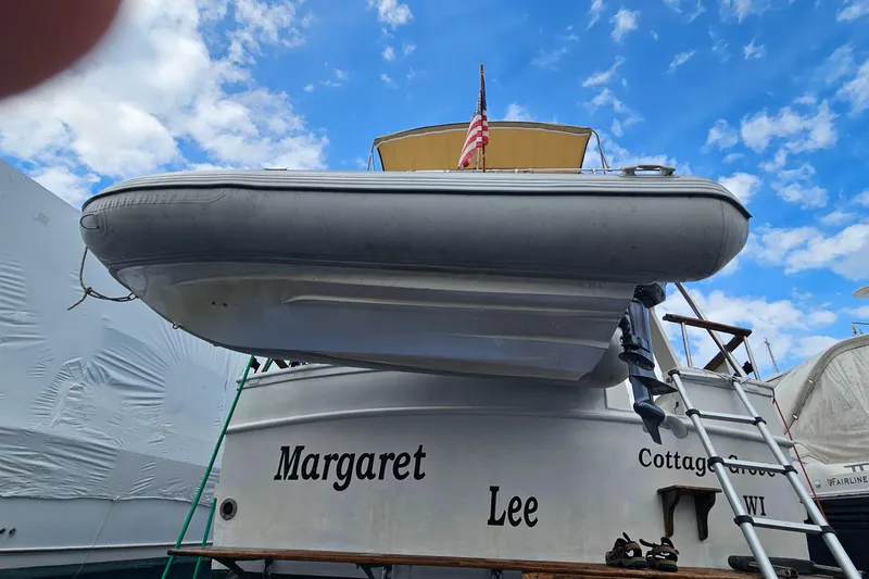 Slide: The Image of 1977 Universal Marine Europa boat with dinghy, ladder, and American flag under a blue sky. - 4