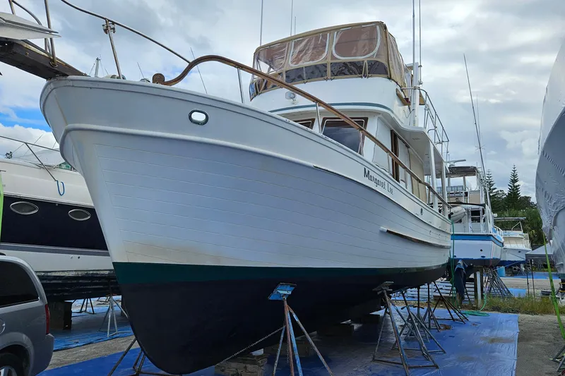 Slide: The Image of 1977 Universal Marine Europa boat on stands, ready for maintenance under cloudy skies. - 5