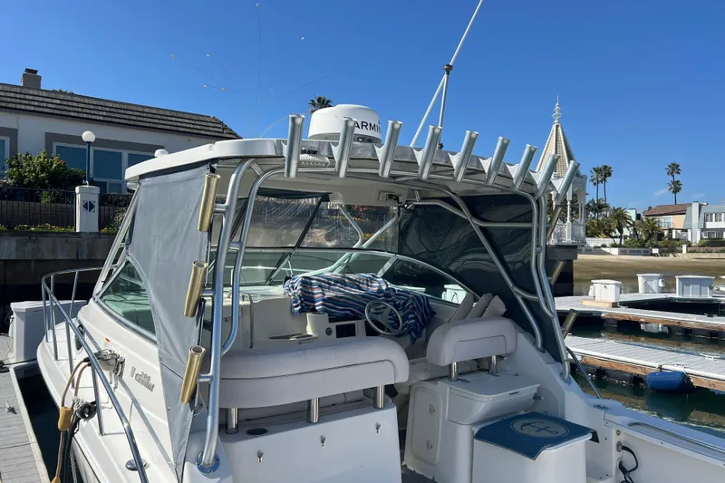 Slide: The Image of 2006 Wellcraft 290 Coastal boat docked, featuring a covered cockpit and fishing rod holders. - 34