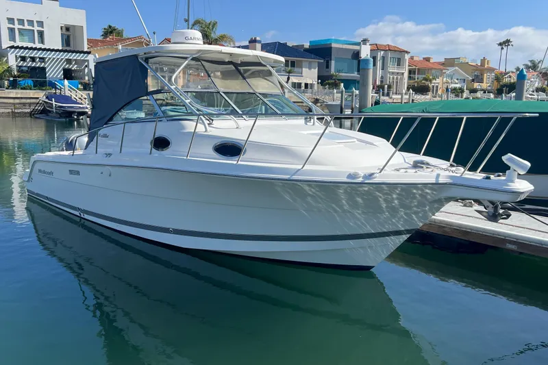Slide: The Image of 2006 Wellcraft 290 Coastal boat docked in a marina, sunny day, waterfront homes. - 4