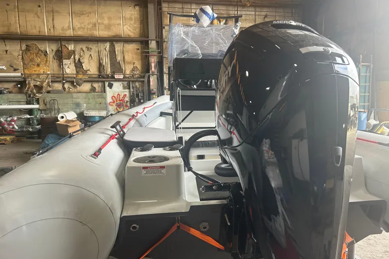 Slide: The Image of 2025 Zodiac Open 6.5 boat with Mercury outboard engine in a workshop setting. - 2