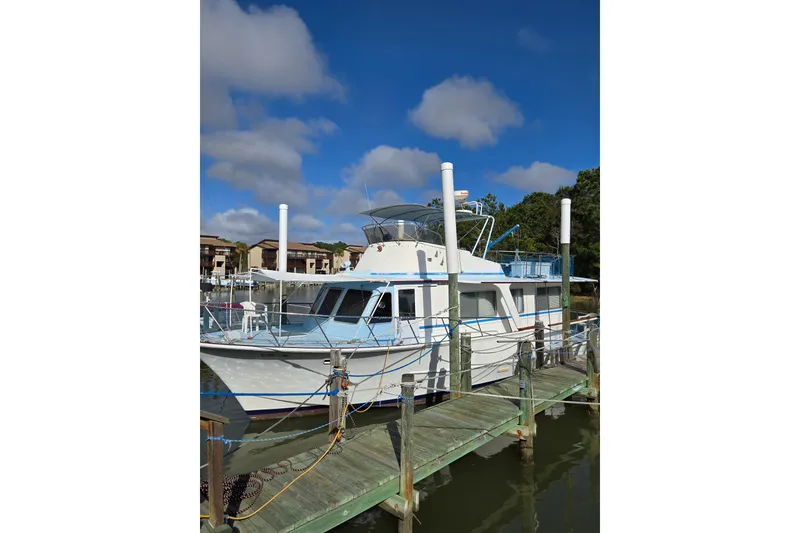 The Image of 1984 Pearson 43 Motor Yacht docked on a sunny day, surrounded by trees. - 0