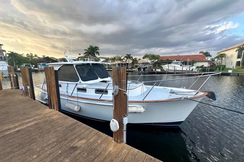 The Image of 2005 Legacy Yachts 34 Express docked at a marina under a cloudy sky. - 0
