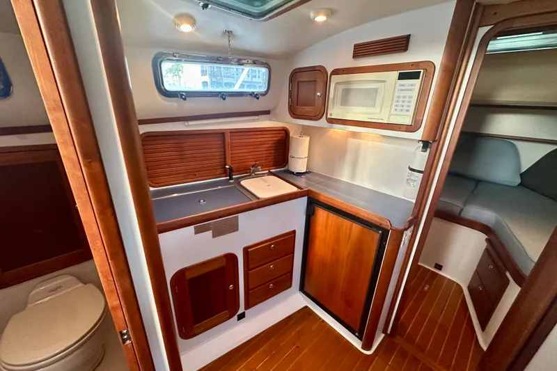 Slide: The Image of 2005 Legacy Yachts 34 Express interior with kitchenette, wood cabinetry, and cozy seating area. - 7