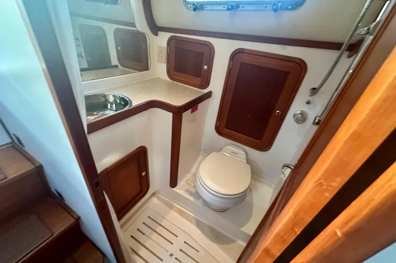 Slide: The Image of 2005 Legacy Yachts 34 Express bathroom with sink, toilet, and wooden cabinets. - 9