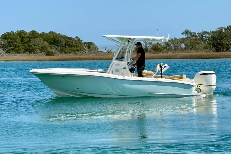 Slide: The Image of 2021 Pioneer 222 Islander boat cruising on calm blue water near a wooded shoreline. - 7