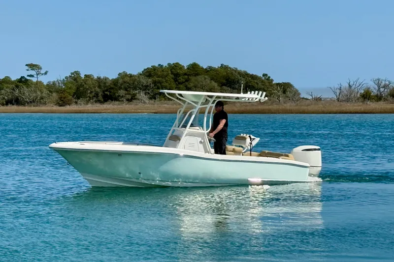 Slide: The Image of 2021 Pioneer 222 Islander boat cruising on calm blue water near a forested shoreline. - 8