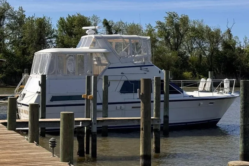 Slide: The Image of 1987 Hatteras 40 Motor Yacht docked by a wooden pier, surrounded by trees. - 1
