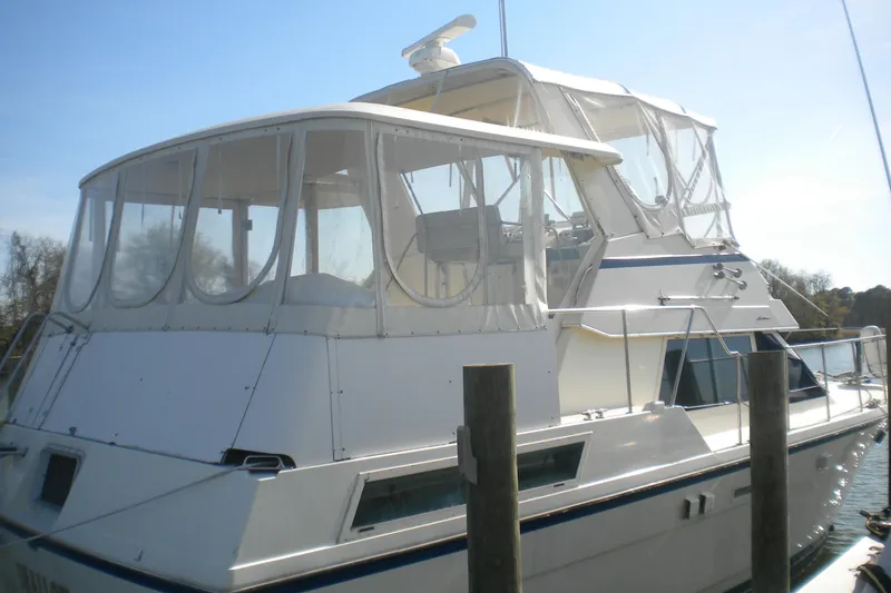 Slide: The Image of 1987 Hatteras 40 Motor Yacht docked, featuring enclosed upper deck and sleek design. - 10