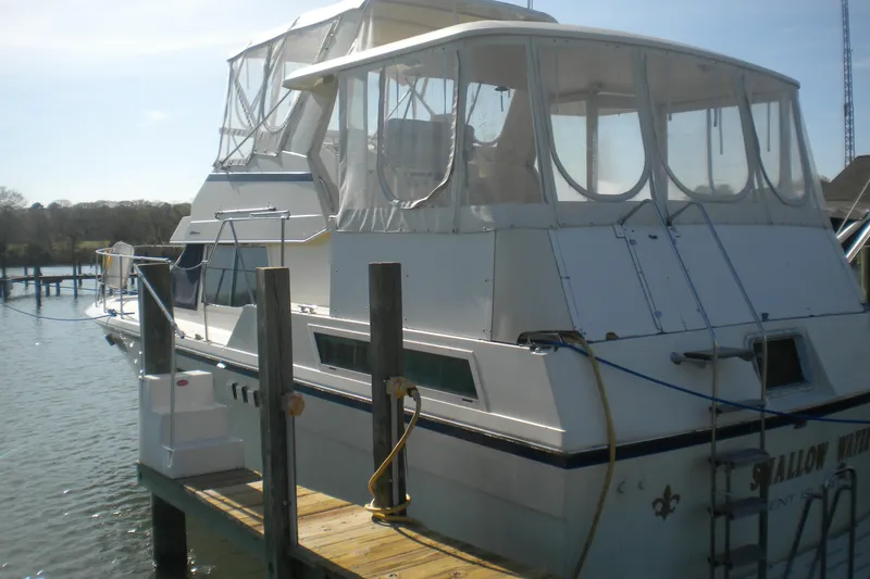 Slide: The Image of 1987 Hatteras 40 Motor Yacht docked, featuring enclosed upper deck and classic design. - 12