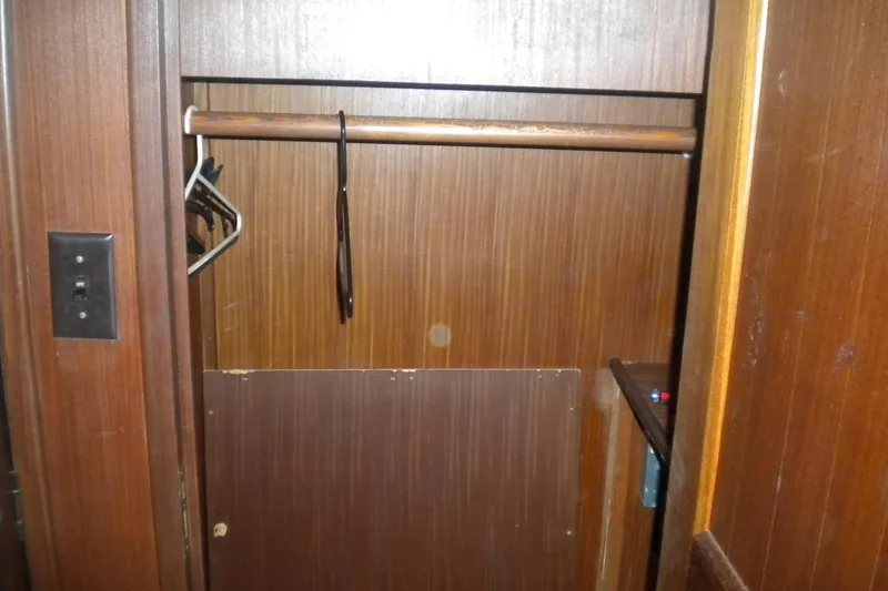 Slide: The Image of Empty wooden closet inside 1987 Hatteras 40 Motor Yacht, featuring hangers and a light switch. - 29