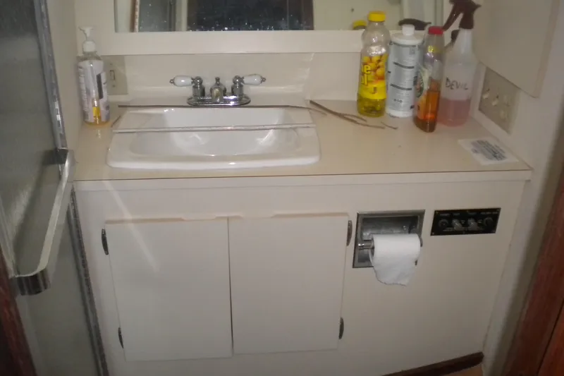 Slide: The Image of Bathroom sink area on a 1987 Hatteras 40 Motor Yacht with cleaning supplies. - 38