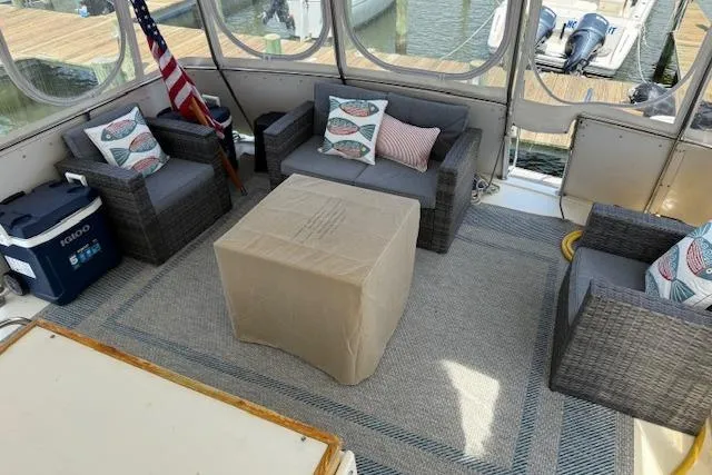 Slide: The Image of 1987 Hatteras 40 Motor Yacht interior with wicker seating, American flag, and cooler. - 4