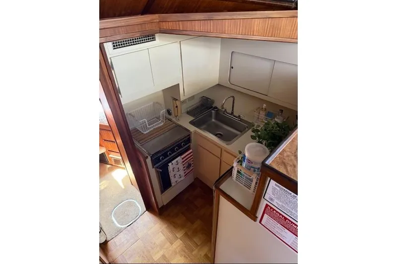 Slide: The Image of Compact kitchen area in a 1987 Hatteras 40 Motor Yacht, featuring a sink and stove. - 8