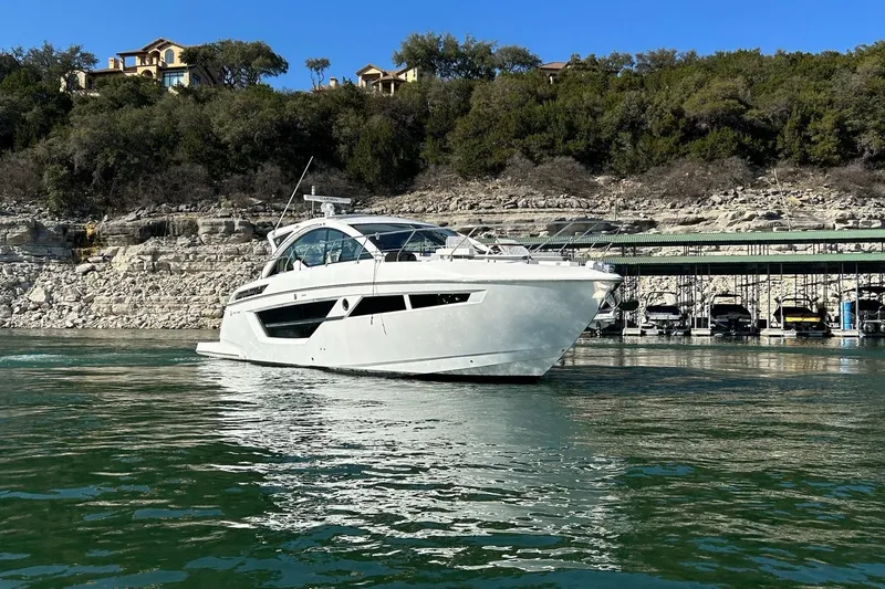 Slide: The Image of 2021 Cruisers Yachts 50 Cantius on serene water near rocky shoreline. - 11