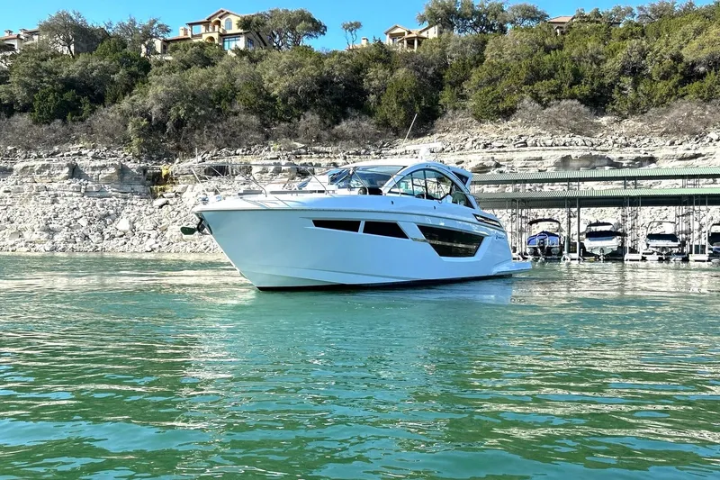 Slide: The Image of 2021 Cruisers Yachts 50 Cantius on serene water near rocky shoreline. - 15