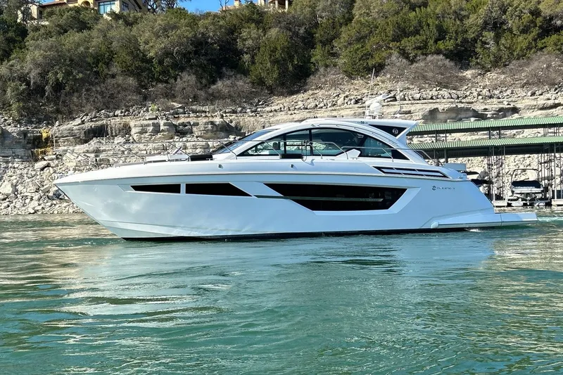 Slide: The Image of 2021 Cruisers Yachts 50 Cantius on serene water with rocky shoreline backdrop. - 16