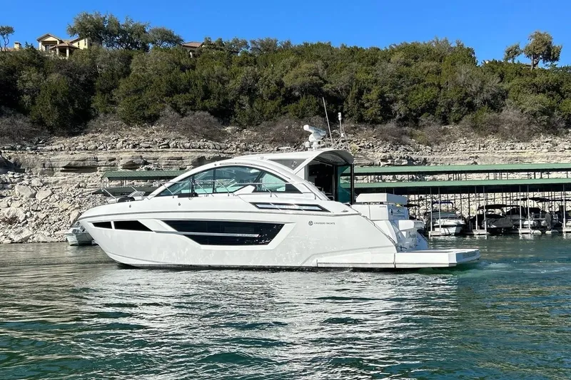 Slide: The Image of 2021 Cruisers Yachts 50 Cantius on serene water with lush green backdrop. - 18
